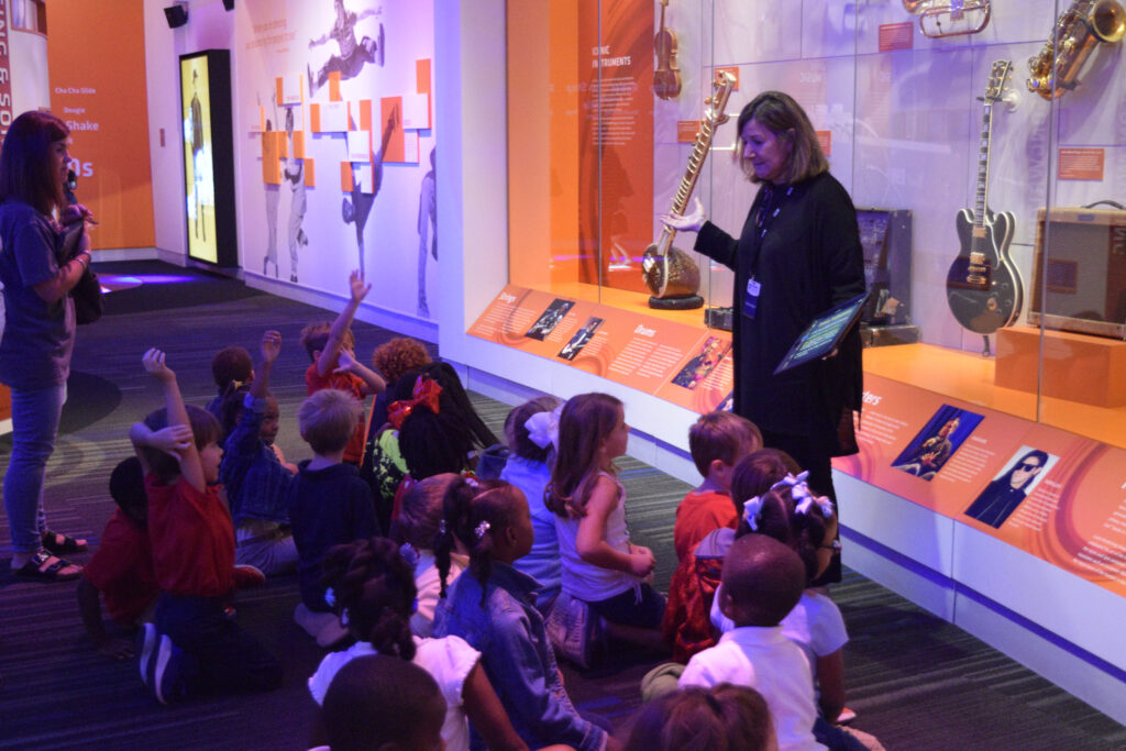 Volunteer showing group of children an exhibit in the Grammy museum.