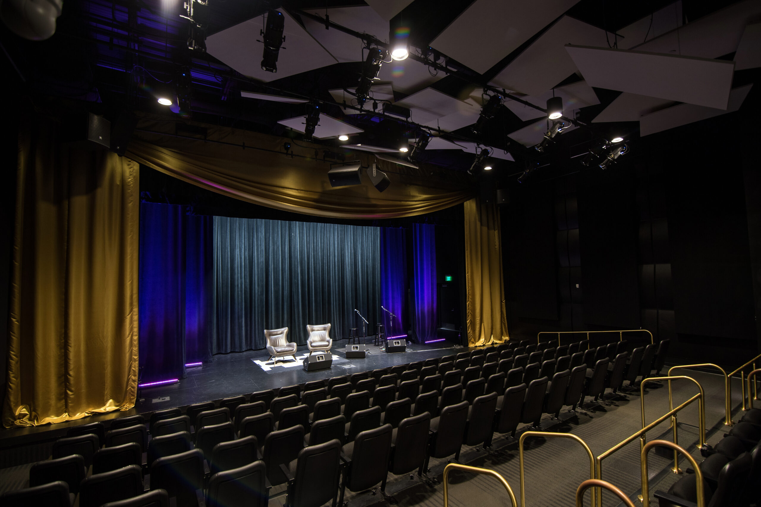 Empty theater with two chairs and two mics on stage.