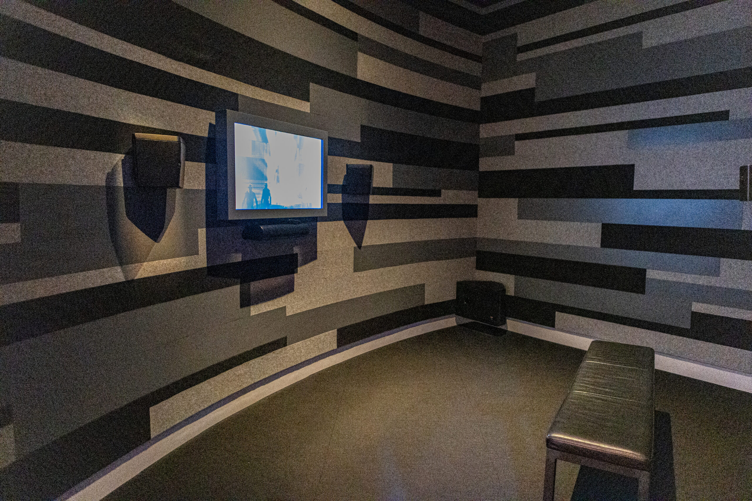 Room with a tv on the wall and a bench.