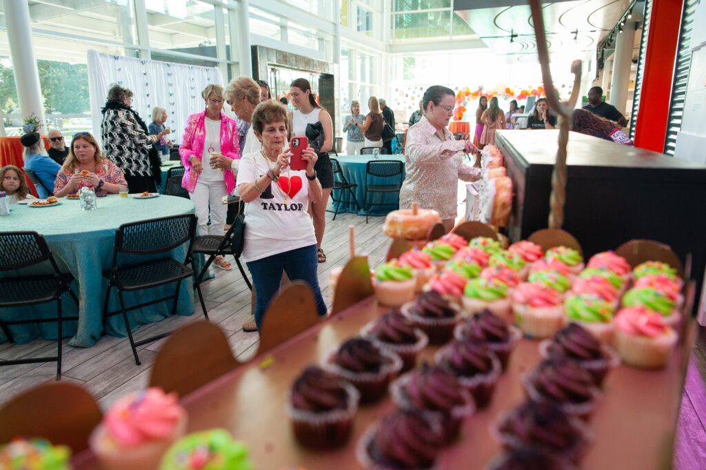 a group of people in a room with cupcakes
