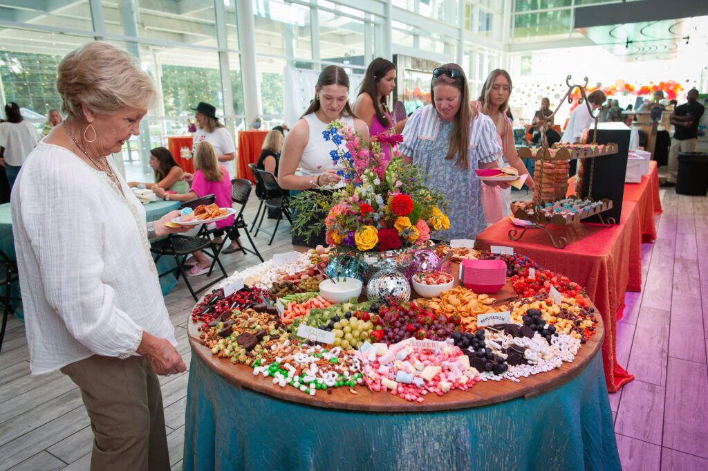a group of people standing around a table with food
