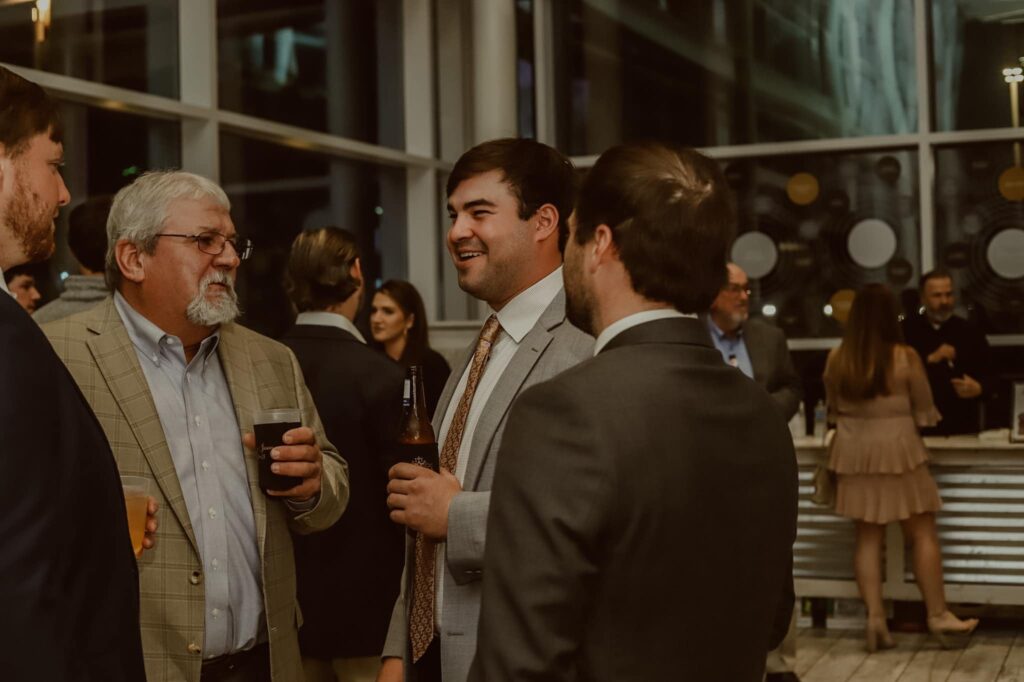a group of men in suits talking and drinking