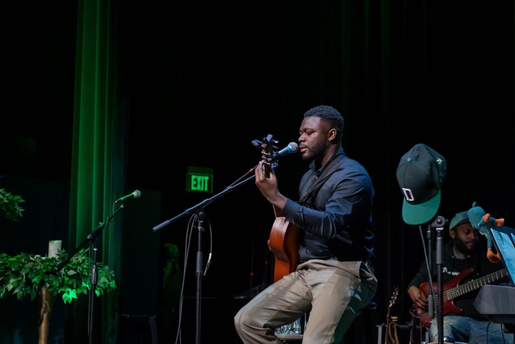 a man playing a guitar and singing into a microphone