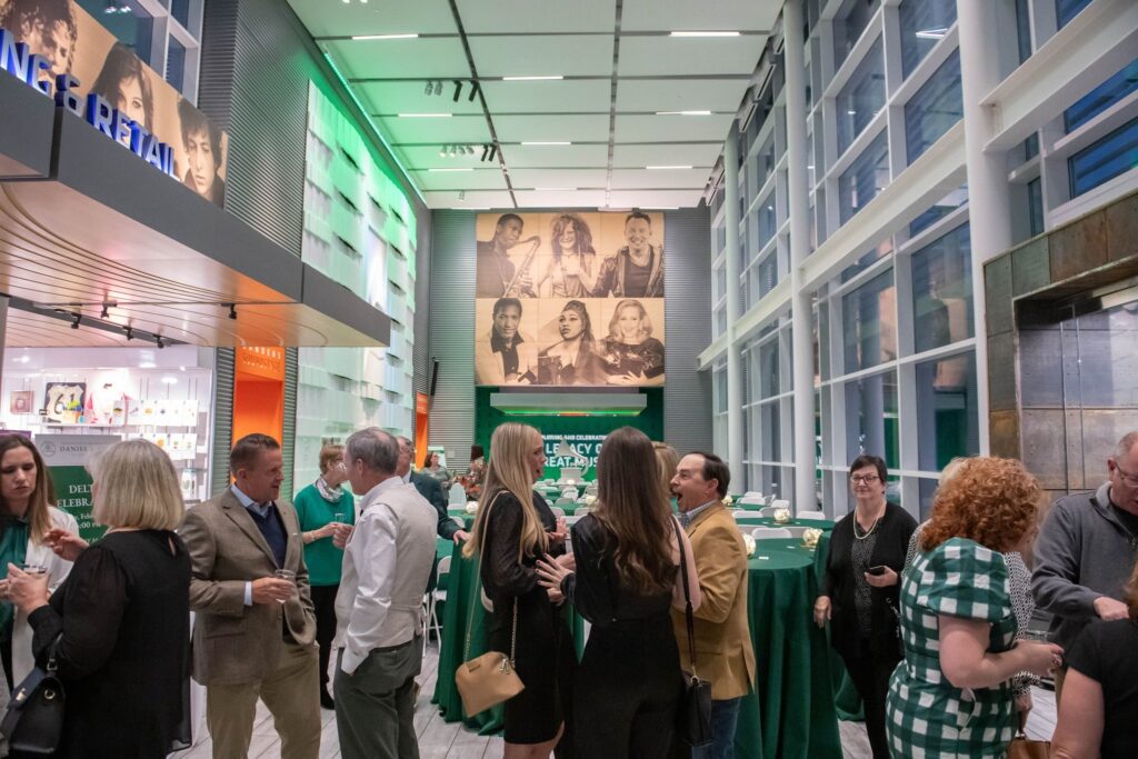 a group of people standing around tables in a room with green walls