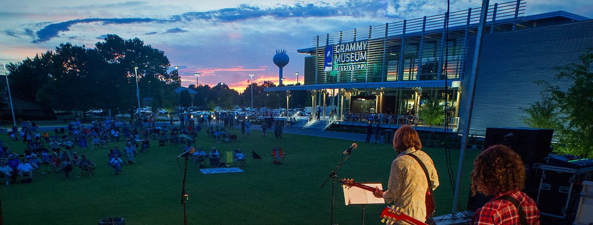 a person playing guitar in front of a building