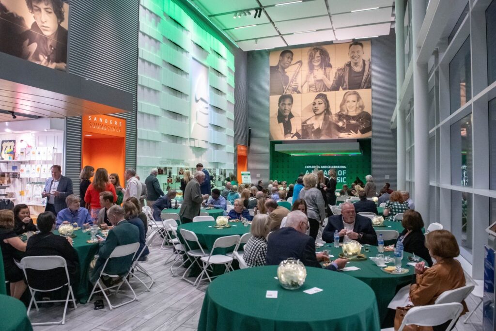 a group of people sitting at tables in a room with green tables