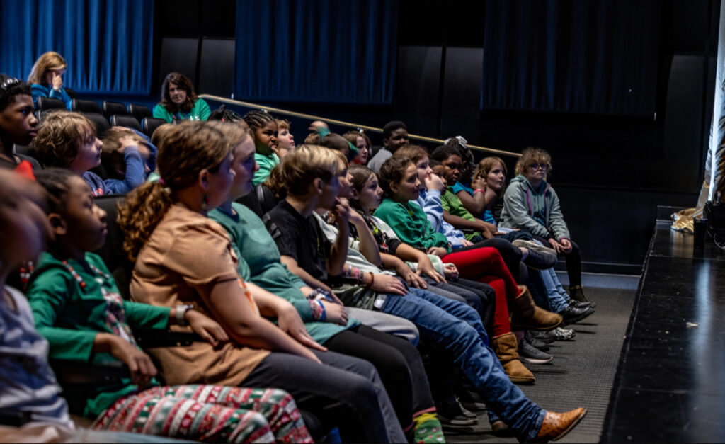 a group of middle school age kids sitting in a row
